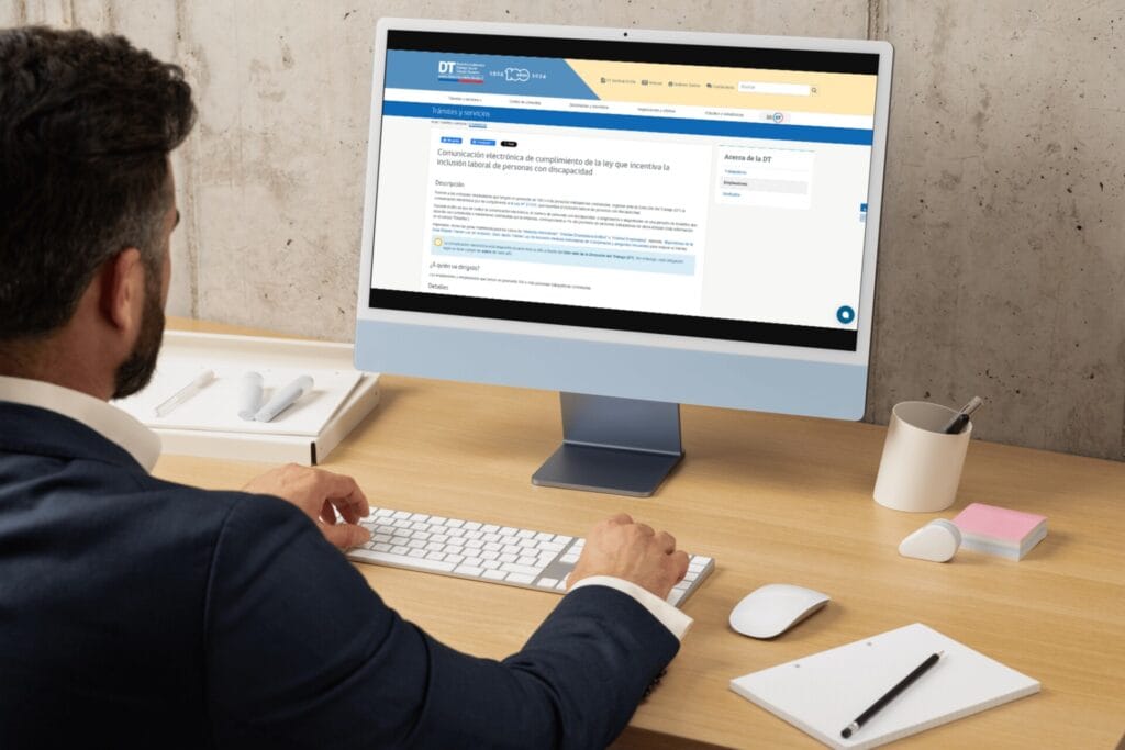 Persona de espalda realizando la comunicación electrónica 2025. Se ve en la pantalla del computador el sitio web de la DT