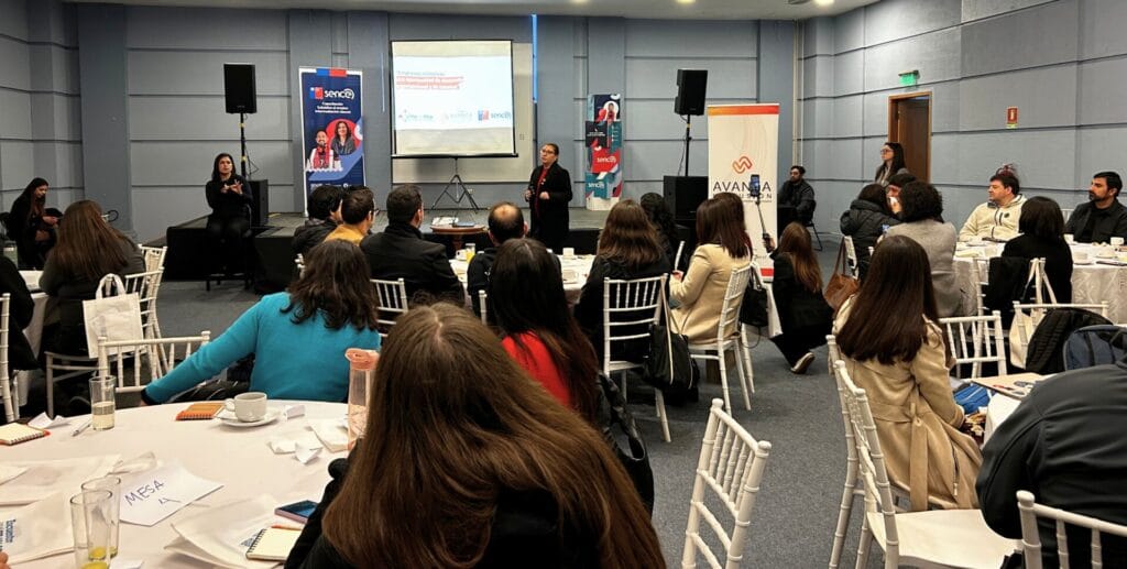 Foto paranorámica del encuentro. Las y los asistentes sentados atentos a la expositora.