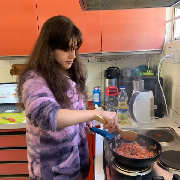 Programa de Inclusión Social Participante del programa en un taller de cocina, mostrando concentración mientras manipula una sartén.